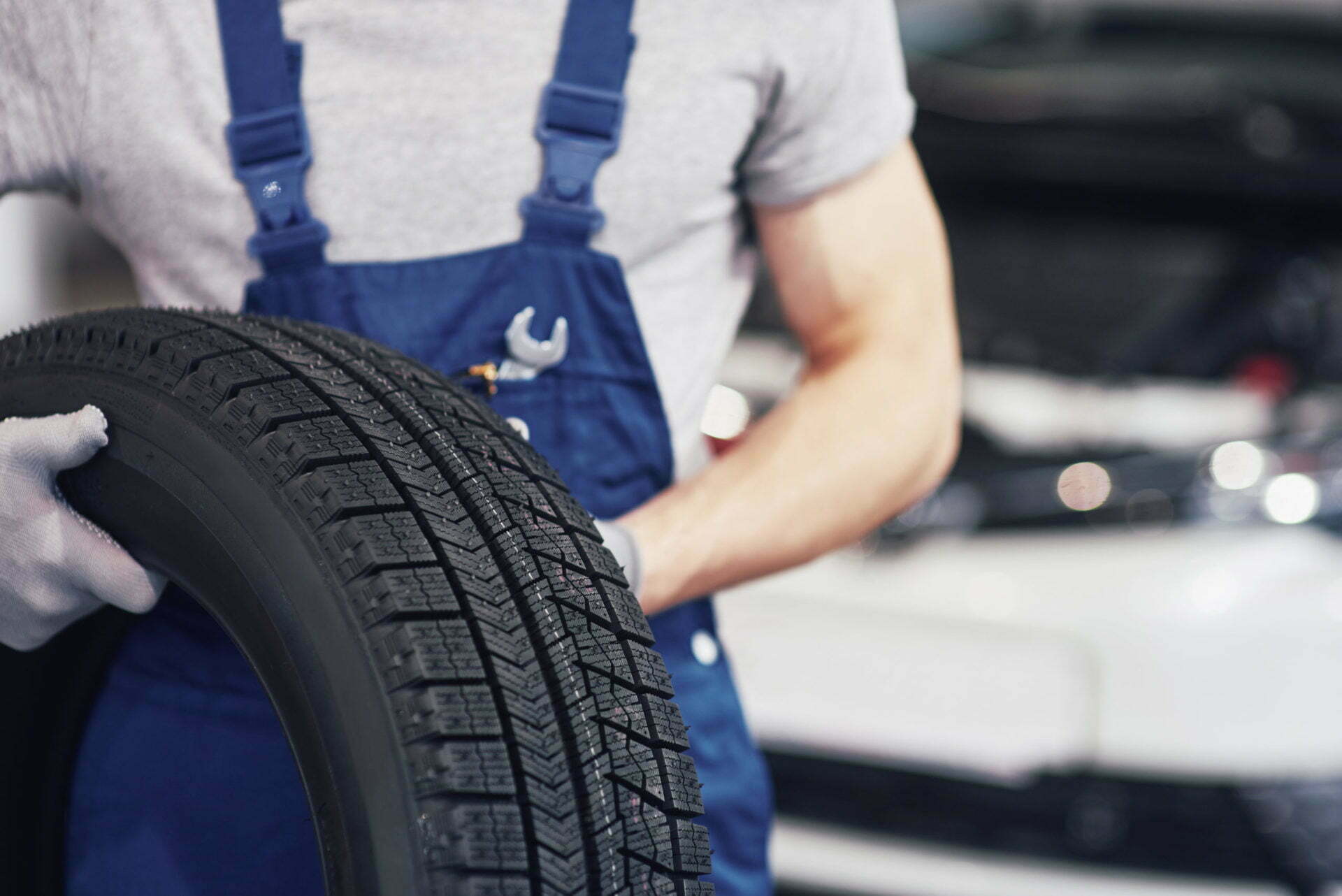Mechanic holding a tire tire at the repair garage. replacement of winter and summer tires Mechanic holding a tire tire at the repair garage. replacement of winter and summer tires.